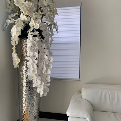 Kaskadierende Phalaenopsis-Orchideen in extrahoher gehämmerter Vase